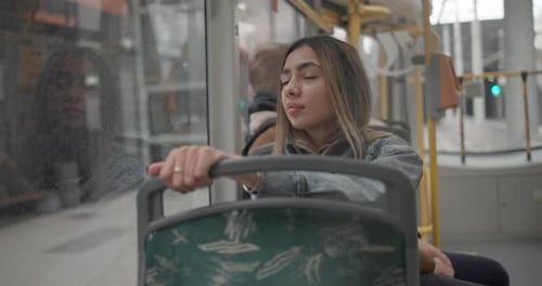 Handheld Video of a Young Girl in a Casual Denim Jacket and Wireless Headphones Riding in a City