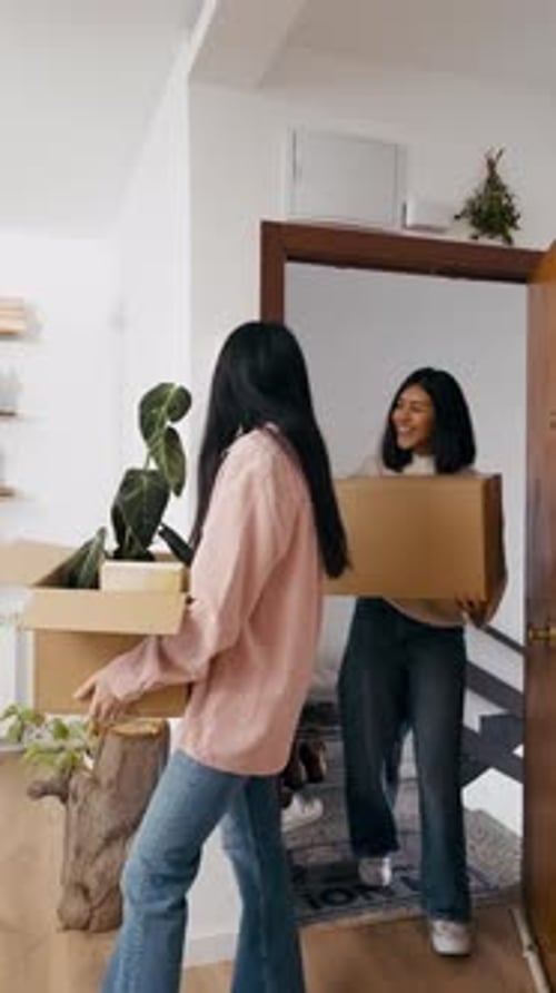Lesbian Couple Carrying Cardboard Boxes Moving Into New Apartment Vertical