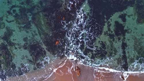 Vista aérea de las olas rompiendo en la orilla con formaciones rocosas