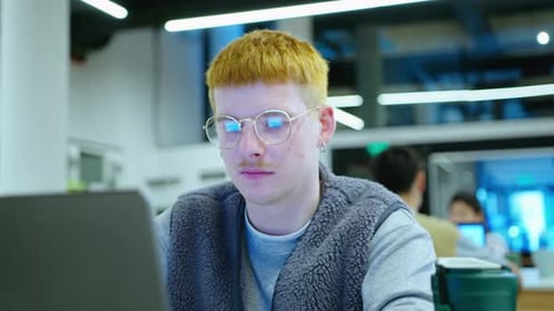 Cheerful Gen Z Man Using Laptop while Working in the Office