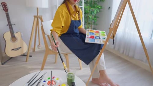 Asian young talented woman artist coloring on painting board in house.