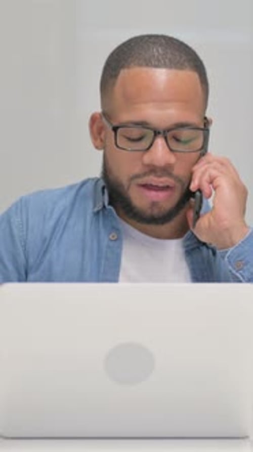 Man using laptop and talking on cell phone