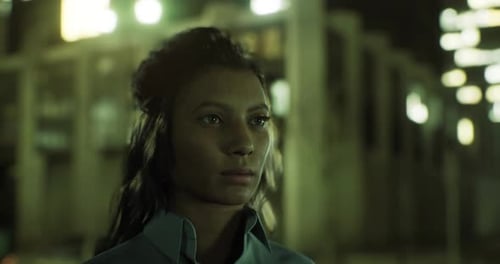 Young Woman Standing Outdoors in Urban Setting with Bright Lights at Night