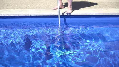 Man cleaning vacuuming pool sunny day