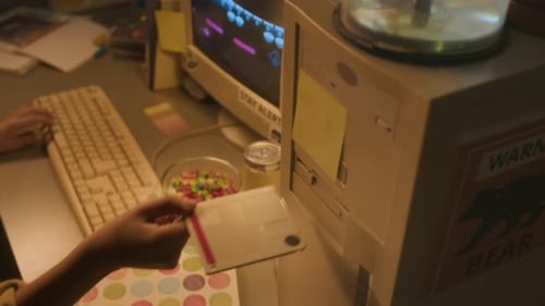 Hand inserts floppy disk into an old computer