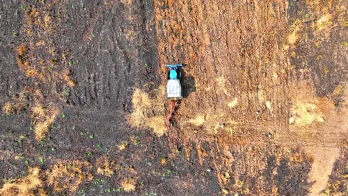 Vista aérea de un tractor arando tierra seca y polvorienta.