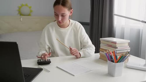 Teenage Student Doing Homework Using Calculator and Laptop