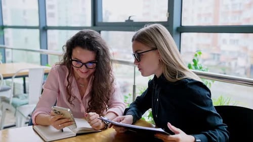 Women Discussing Business at a Table with Smartphone