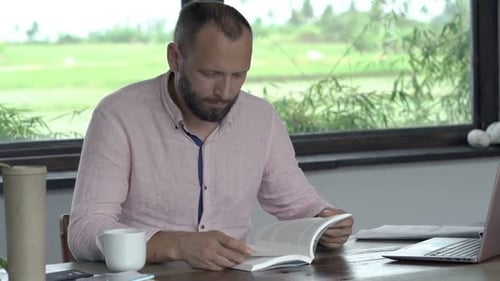 Man reading a book indoors during daytime