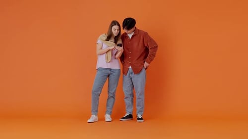 Woman and Asian Man Winning Game on Mobile Phone in Studio