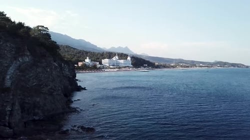 Rocky Coastline Meeting Tranquil Blue Ocean Near Luxurious Resort