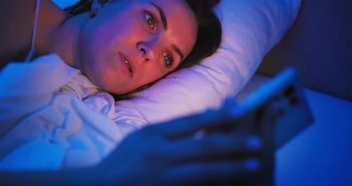 Woman Using Cellphone While Lying Awake in Bed