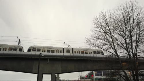 Petit train passant sur un petit pont par une journée sombre, ciel gris en arrière-plan.