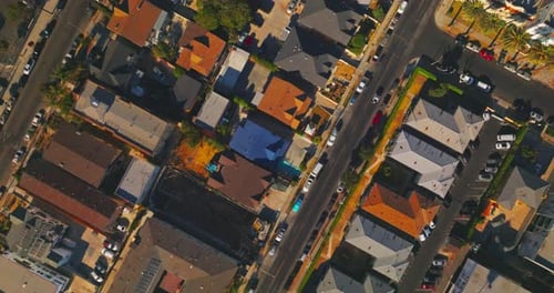 Flying over the roofs and streets of sunny Los Angeles. Numerous cars stand and move by the roads