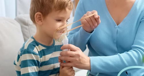 Child Using Nebulizer at Home with Parent