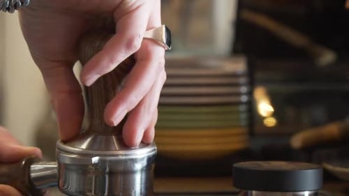 Skilled Barista Pressing Ground Coffee In Portafilter With Tamper. close up
