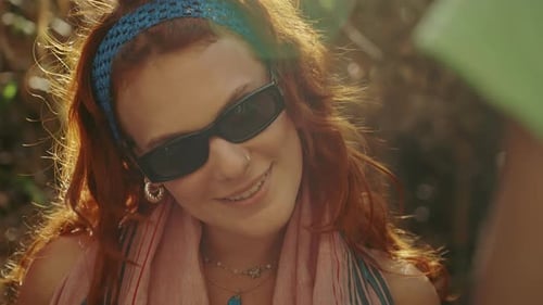 Close up view of a young woman with sunglasses and tattoos posing for the camera