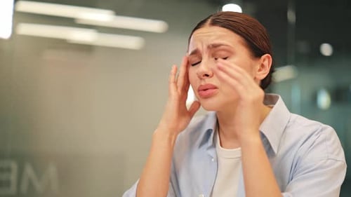 Young Woman Suffering From Severe Headache in Office