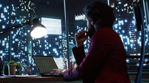 Man Works Late at Desk with Laptop at Night