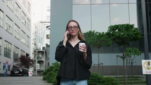 Young Woman Talking on Phone with Coffee Outdoors