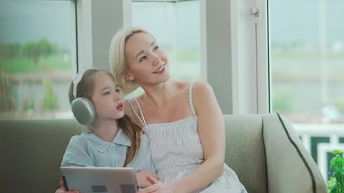 Mother and Daughter Using Tablet on Couch Together