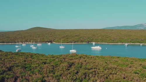 Aerial drone video of paradise island bay with crystal clear ocean visited by yachts and sail boats.