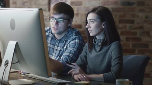 Man and Woman Collaborating on Computer in Office