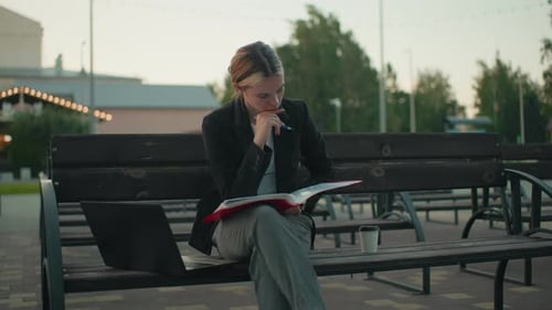 Young Woman Works on Bench in City Park