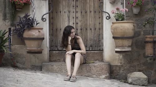 Young Woman Sits On Steps by Wooden Door