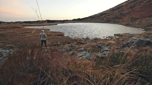 Grass Moving Away to Reveal Man Standing By Pond