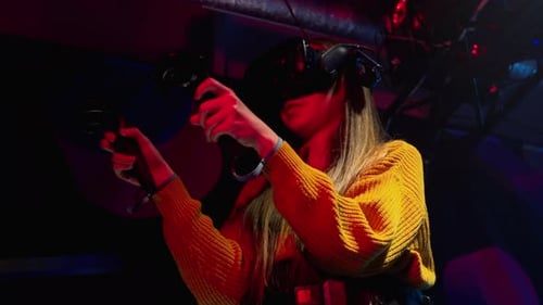 Woman playing VR games in a studio with blue pink neon lights