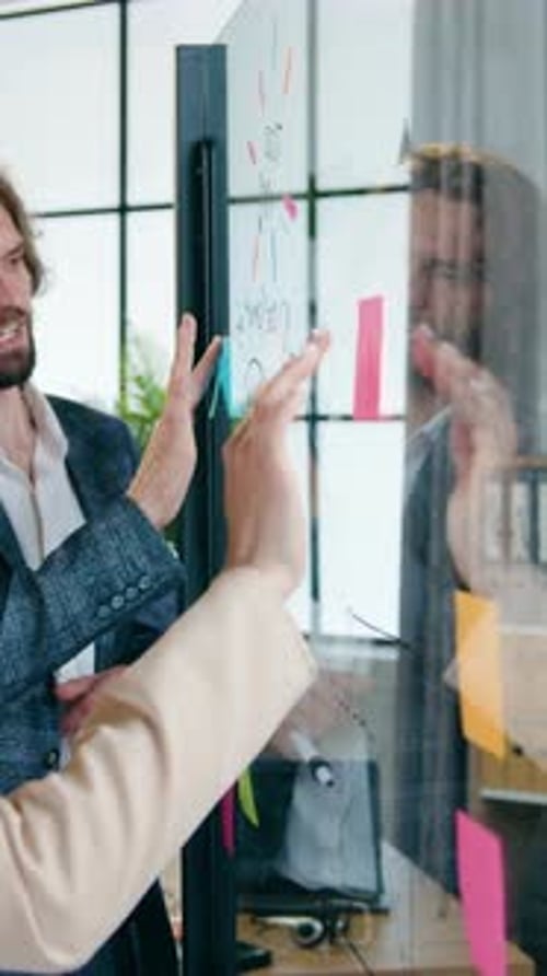 Business Professionals Collaborate on Glass Whiteboard