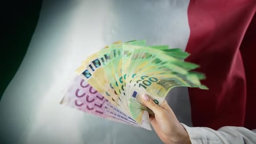 Hand Displaying Euro Notes Against Italian Flag