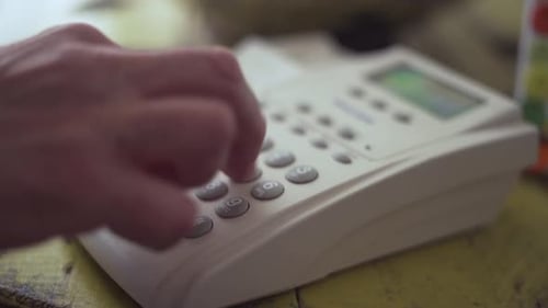 Person Dialling a Corded Phone and Hanging Up