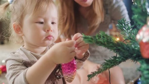 Infant Decorating Christmas Tree with Adult Assistant