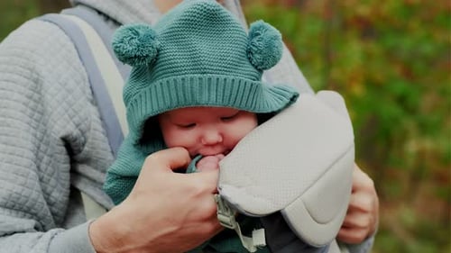 Young Father with His Newborn Baby in a Sling Walking in the Autumn Forest The Concept of a Happy