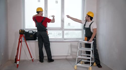 Apartment Repair in the Room Two Men Workers Measures the