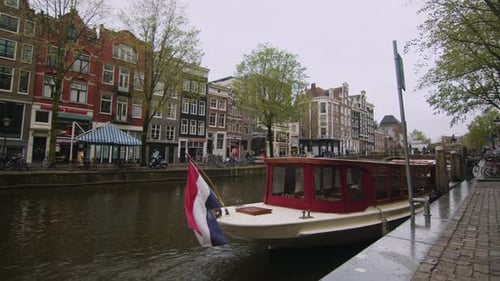 Amsterdam, Holland, Boat in canal with holland flag on cloudy day, static , wide angle shot 4K