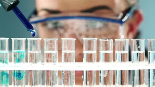 Scientist Drops Blue Liquid Into Test Tubes