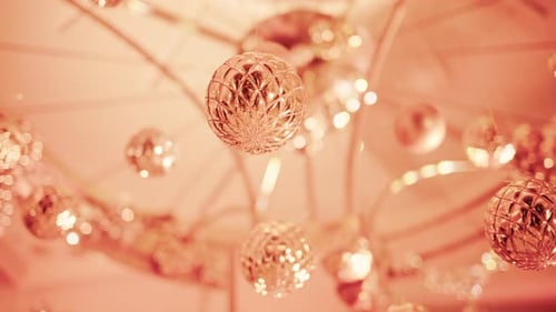 Close up view of elegant golden Christmas ornaments suspended indoors with warm festive lighting