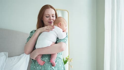Loving Mother Holding Newborn Baby in Bedroom