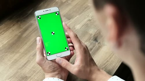 Ein moderner Geschäftsmann verwendet das Handheld-Handy mit Greenscreen-Touchpad und gestikuliert in Nahaufnahme