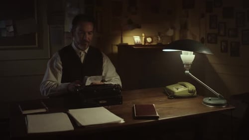 Man Writes at Vintage Typewriter at Wooden Desk