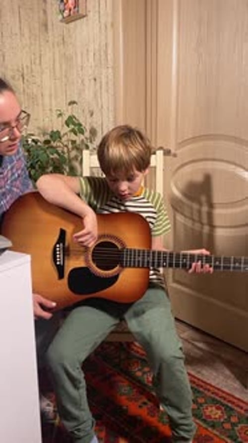 Child Receiving Guitar Lesson at Home