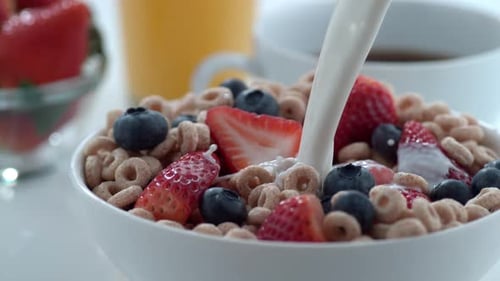 Milk Pouring on Breakfast Cereal with Strawberries Blueberries