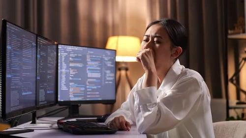 Programadora asiática bostezando mientras crea una innovadora ingeniera de software que desarrolla una aplicación, un programa