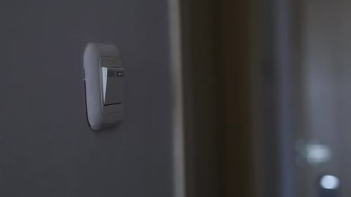 Close up shot of a man's hand turning light switch on in the room
