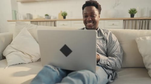 Man Video Chats on Laptop While Relaxing on Couch