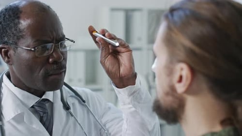 Doctor Examines Patient with Penlight in Office