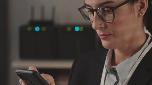 Female System Administrator Using Smartphone in Server Room